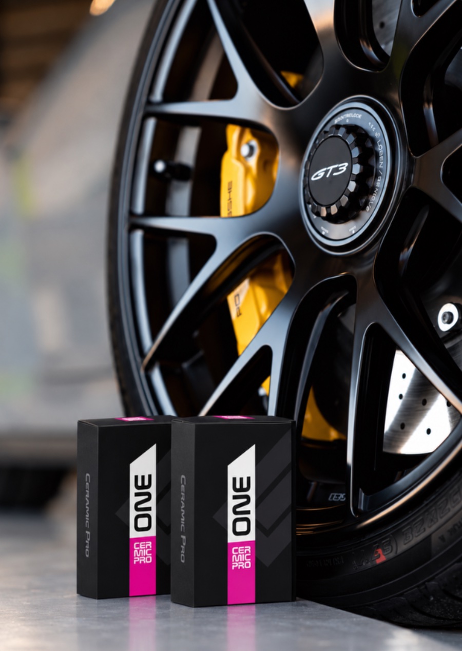 Two Ceramic Pro ONE coating boxes beside a black Porsche 911 GT3 wheel with yellow calipers