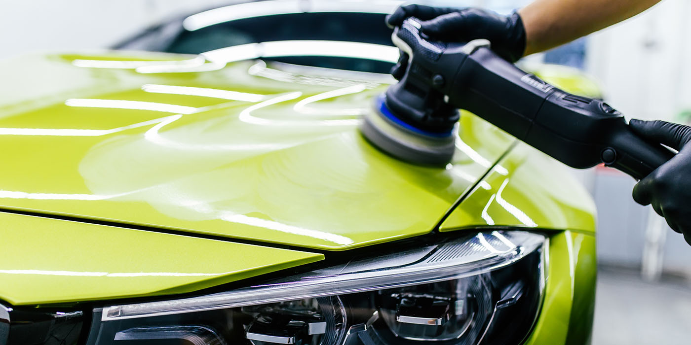 Orbital polisher correcting paint on a chartreuse-green sports car hood at Ceramic Pro Fuel House