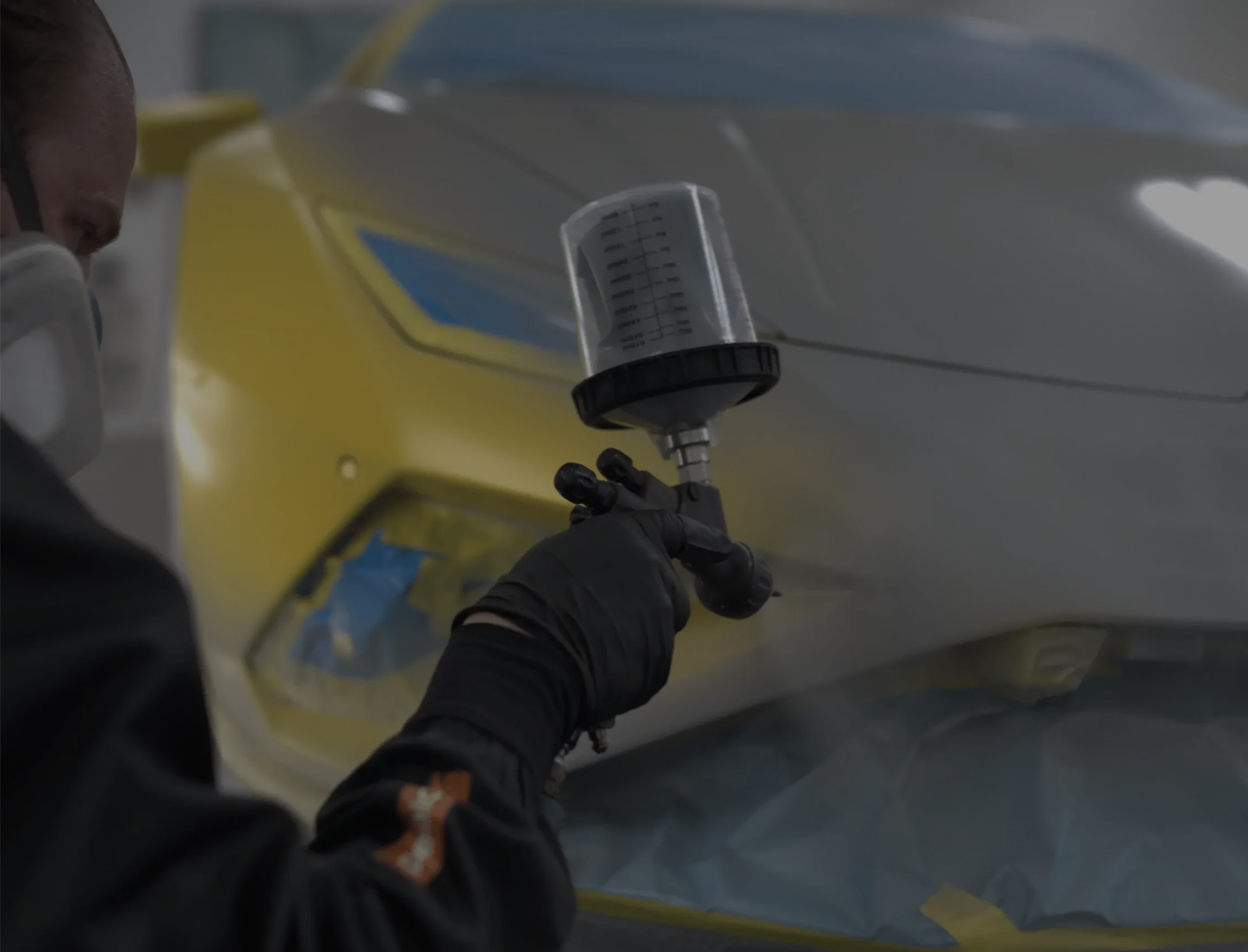 Peelclear being spray-applied to a supercar in a booth by a Ceramic Pro technician