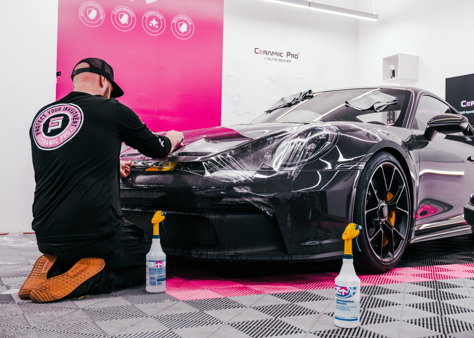 Ceramic Pro Elite Dealer technician installing KAVACA Paint Protection Film on a black Porsche 911 GT3 front bumper